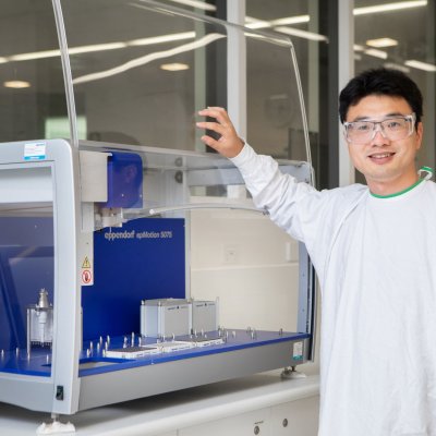 Dr Chun Xu in the laboratory with his hands on a piece of equipment